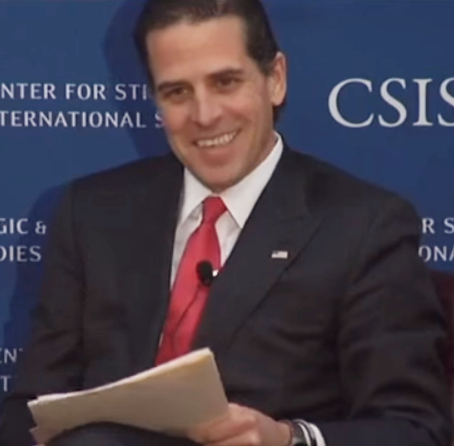 Man in a suit smiling at a conference panel