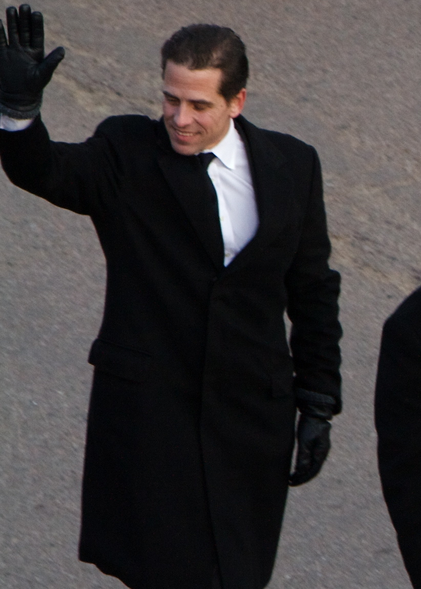Man in a long black coat waving