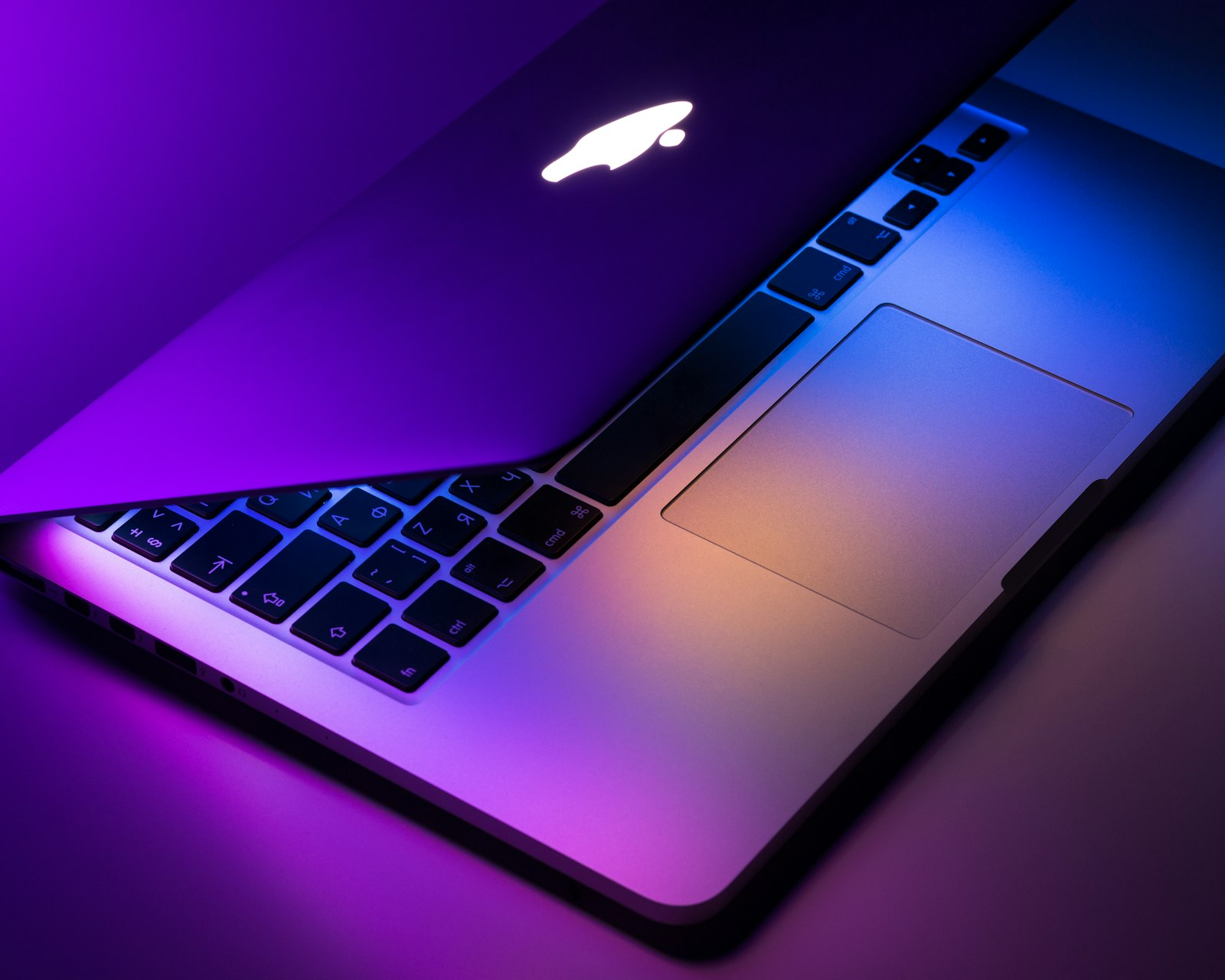 Silver MacBook Pro photographed under coloured light